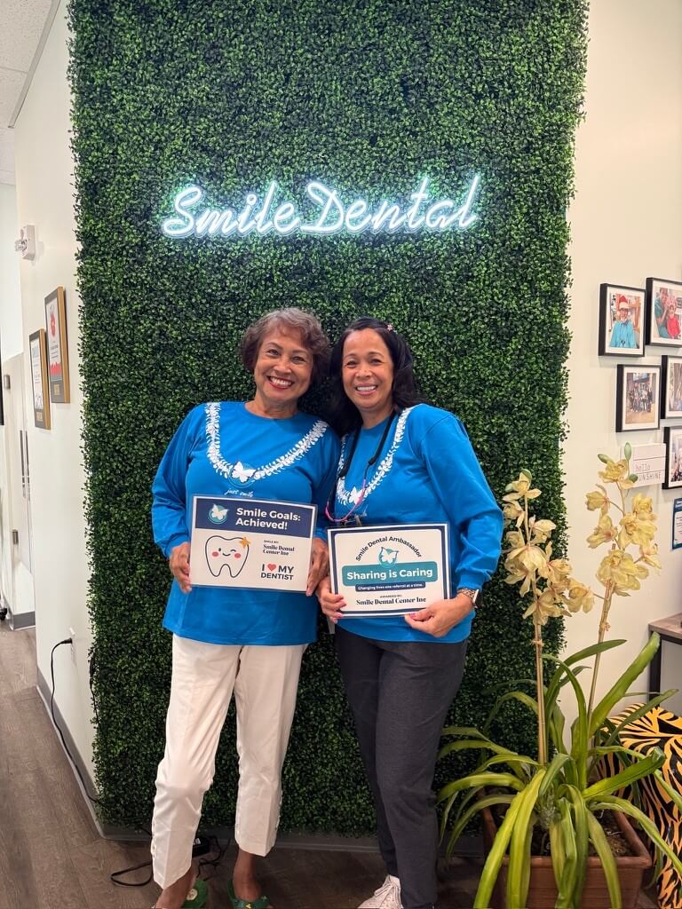 Patients celebrating their smile goals with award signs at Smile Dental Center
