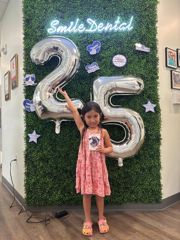 Young patient with Smile Dental Center's 25th-anniversary balloons