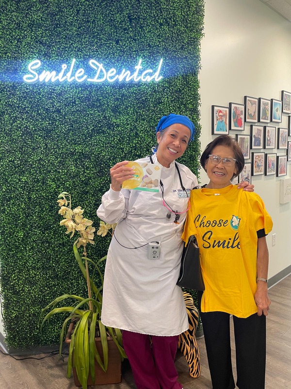 Smiling in front of the Smile Dental wall