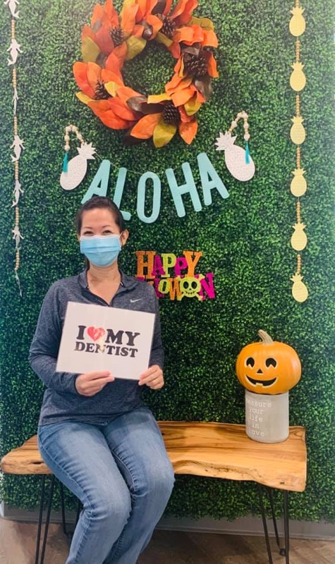 A happy patient holding an I love my dentist sign