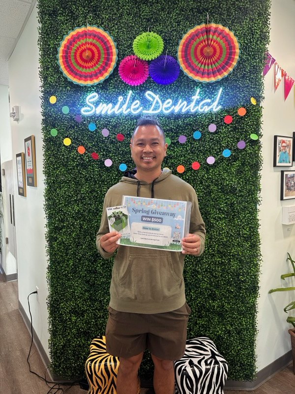 A patient celebrating at the Smile Dental wall