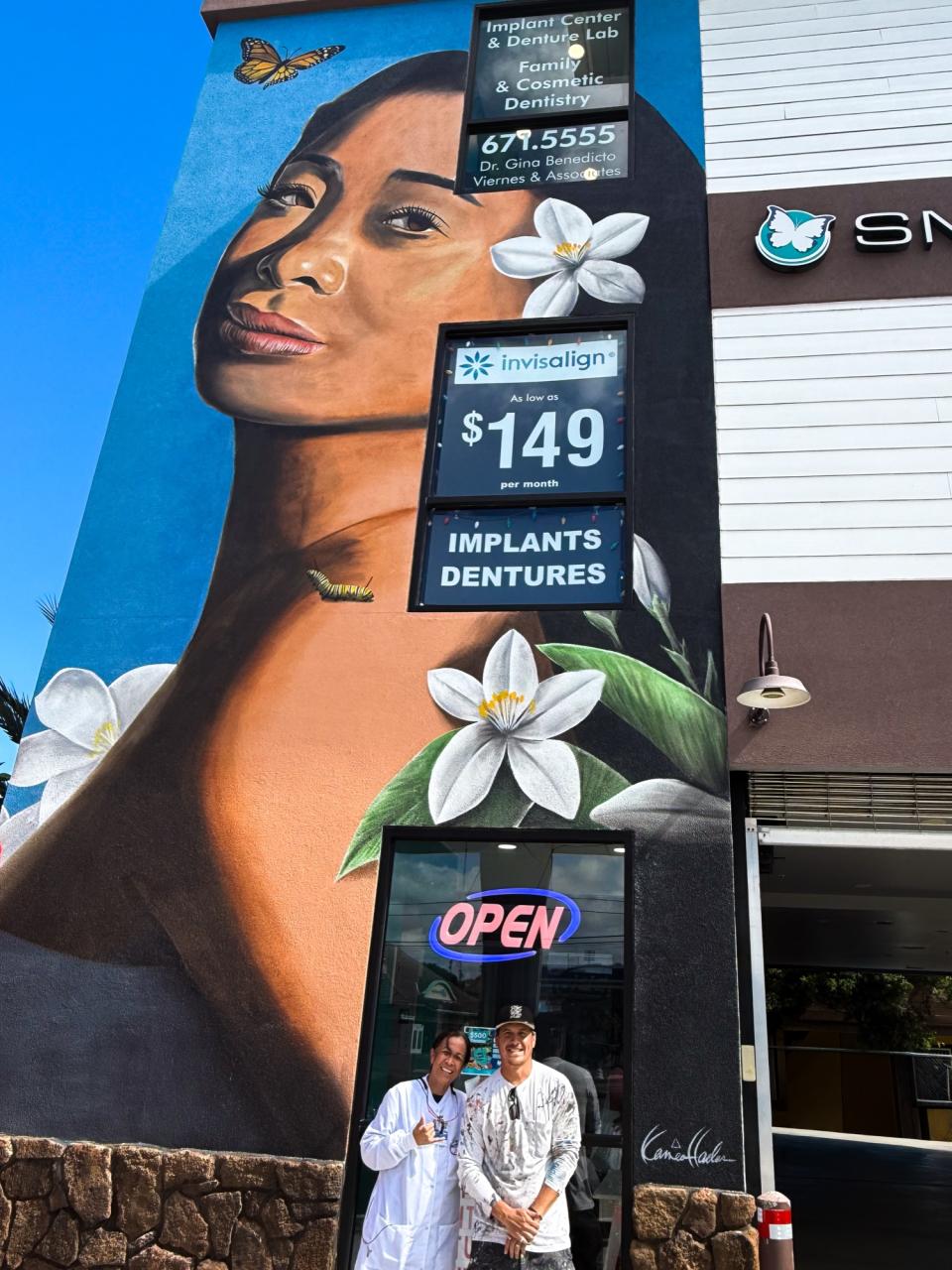 Dr. Gina Viernes and artist Kamea Hadar standing in front of the finished mural at Smile Dental Center